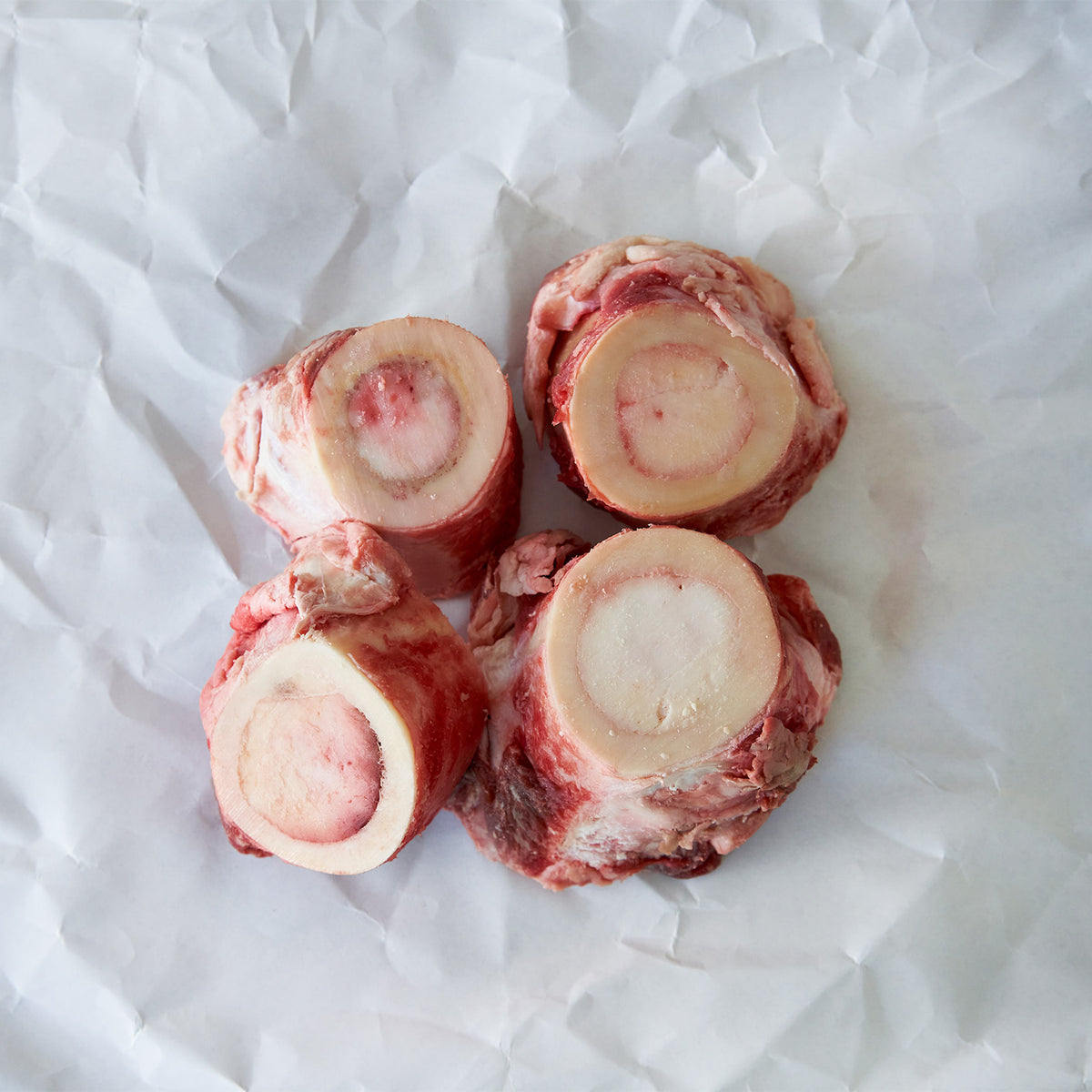 Four raw beef bones on a white paper background