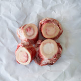 Four raw beef bones on a white paper background