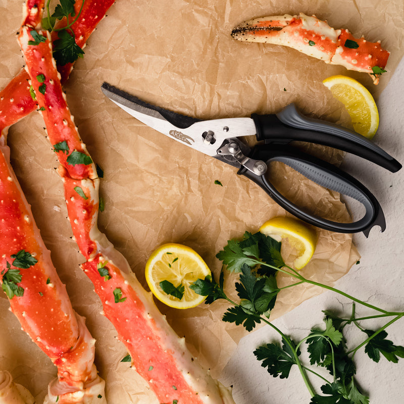 Raw crab legs with a pair of shears and lemon wedges on brown paper