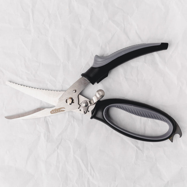 Pair of kitchen shears with black handles on a white fabric background