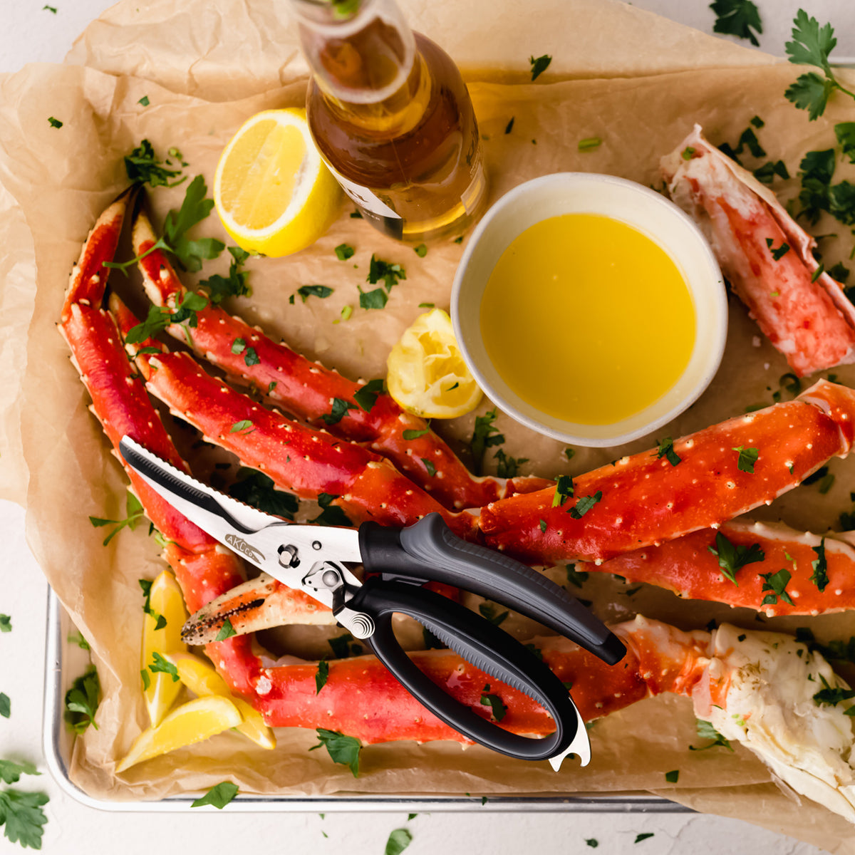 Raw king crab legs on a tray with lemon wedges, a bottle of beer, and a bowl of butter sauce.