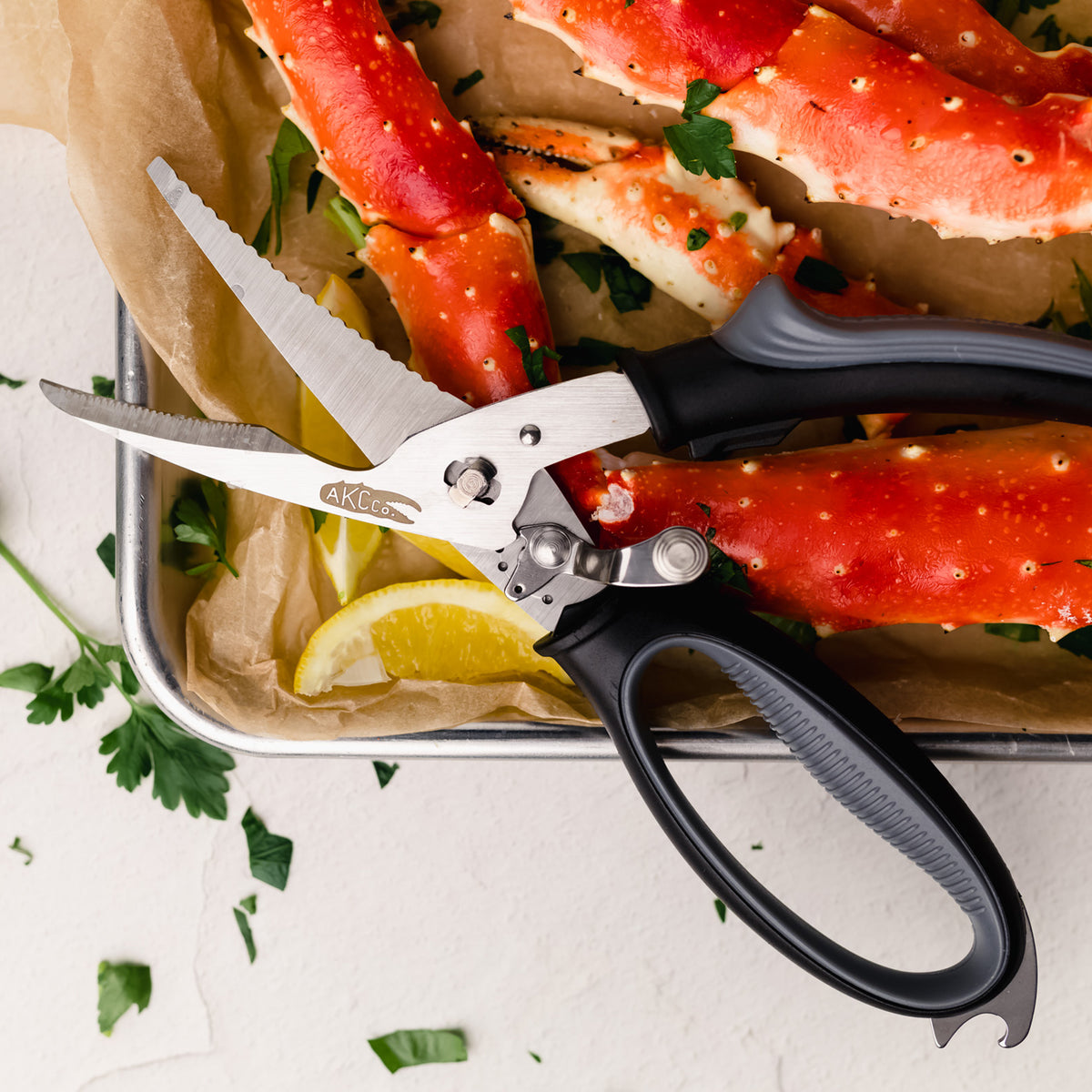 Klee kitchen shears on a tray with crab legs and lemon slices.