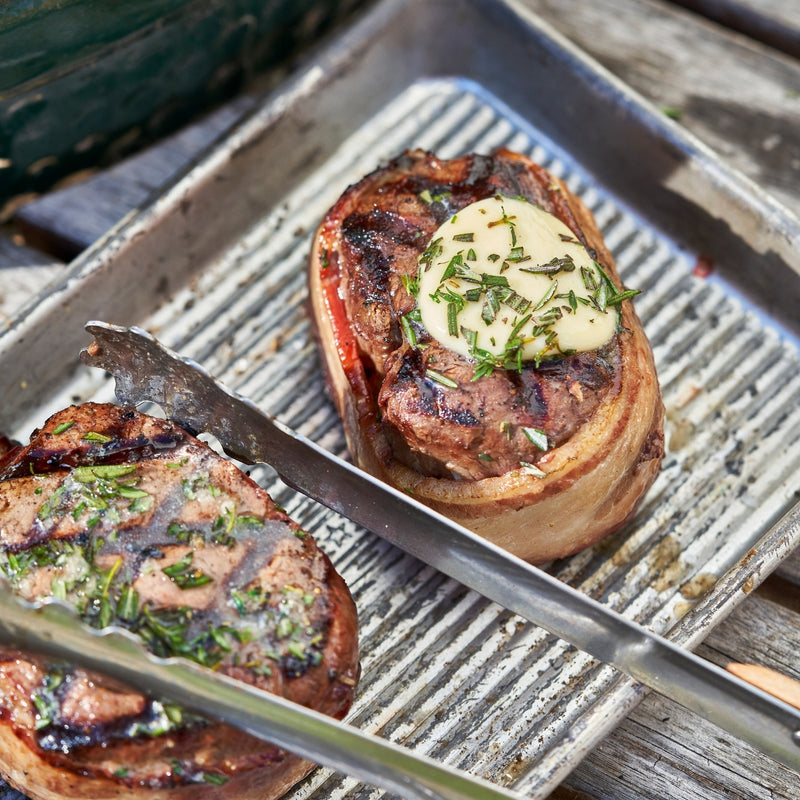 Grilled meat dish with butter and herbs on a grill pan