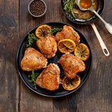 Plated cooked chicken thighs surrounded by rosemary and lemon