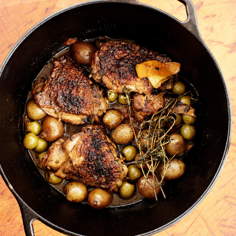 Cooked chicken thighs in cast iron skillet with potatoes and seasonings