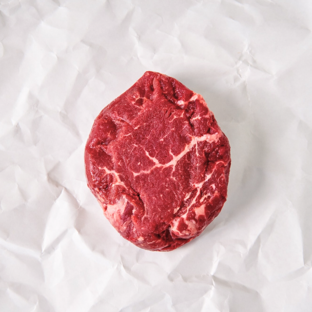 Raw steak on a white textured surface