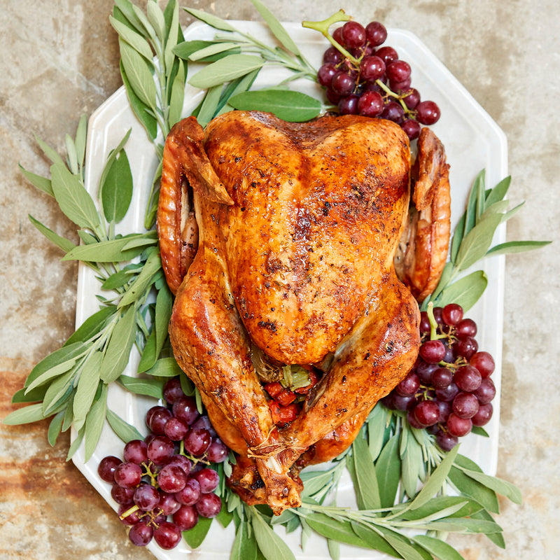 Roasted turkey on a platter with green herbs and red grapes