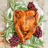 Roasted turkey on a platter with green herbs and red grapes