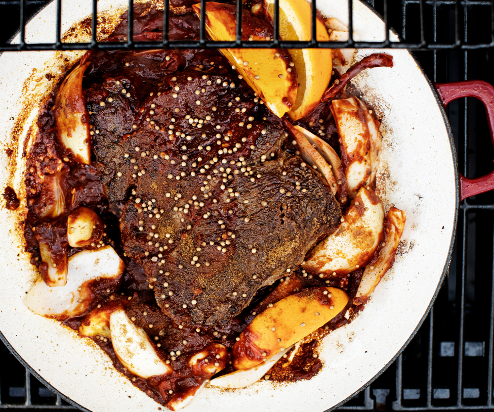 Roasted meat with onions and garlic in a white dish on a grill