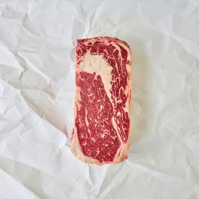 Marbled raw steak on a white crumpled paper background