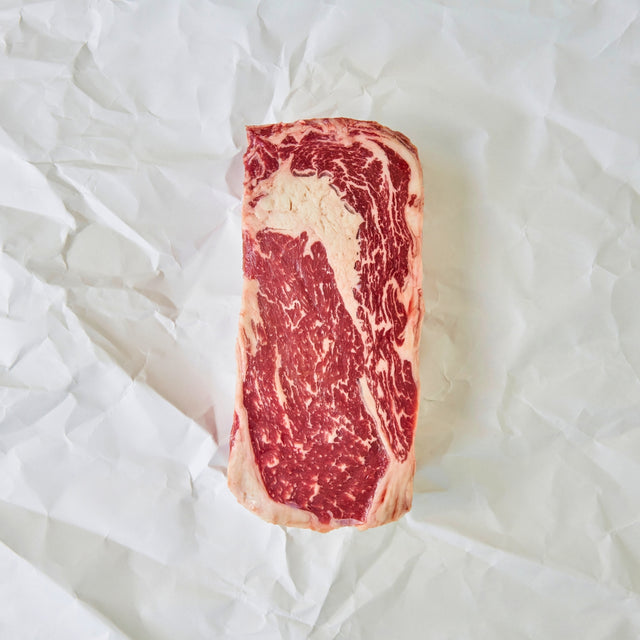 Marbled raw steak on a white crumpled paper background
