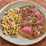 Sliced steak with a side of couscous on a plate