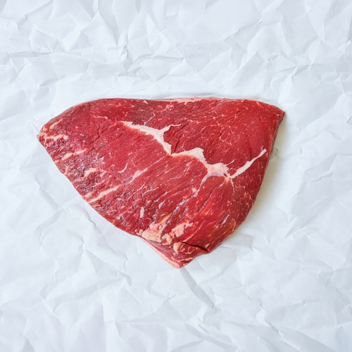 Triangular piece of raw red meat on a white crumpled paper background