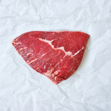 Triangular piece of raw red meat on a white crumpled paper background