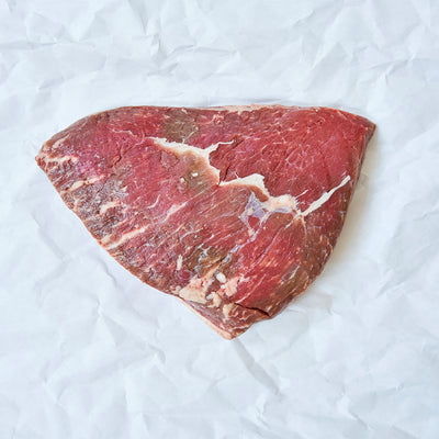 Raw piece of beef (Picanha) on a white crumpled paper background