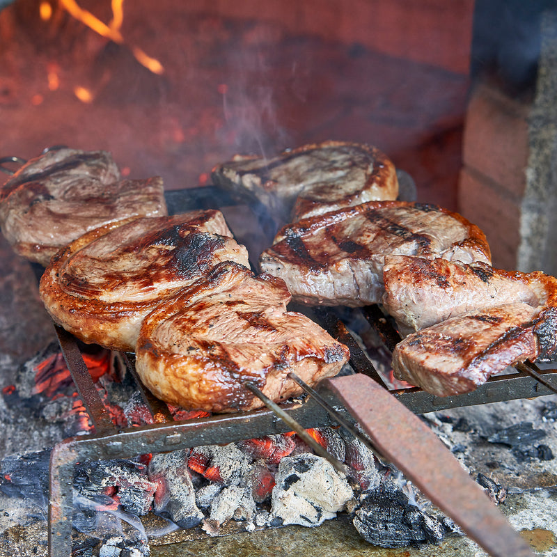Grilled meat on a barbecue with flames and coals in the background