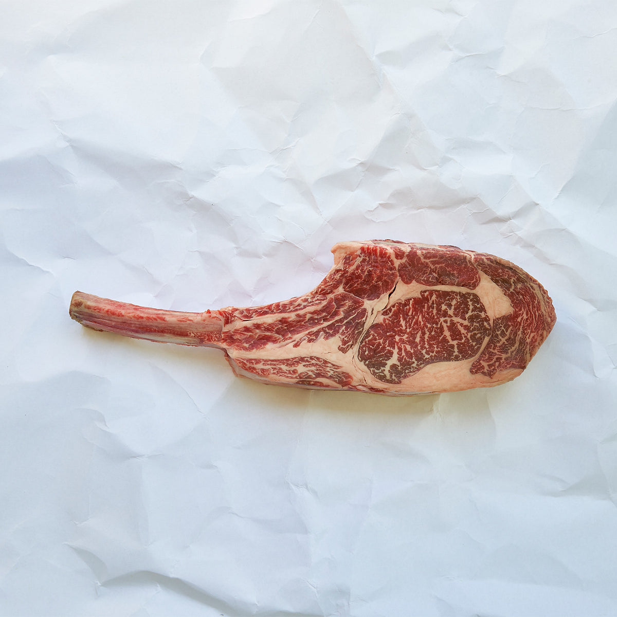 Raw ribeye steak on a white textured surface