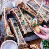 Baked bone marrow with herbs on a wooden surface