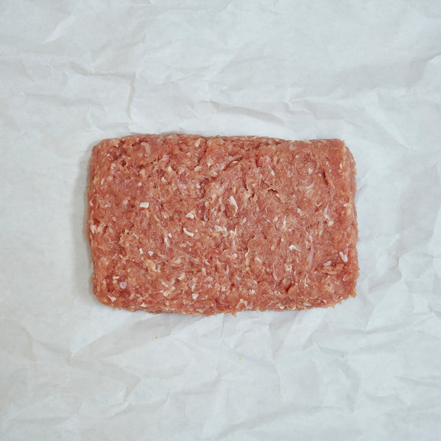 Block of ground chicken on a white paper background
