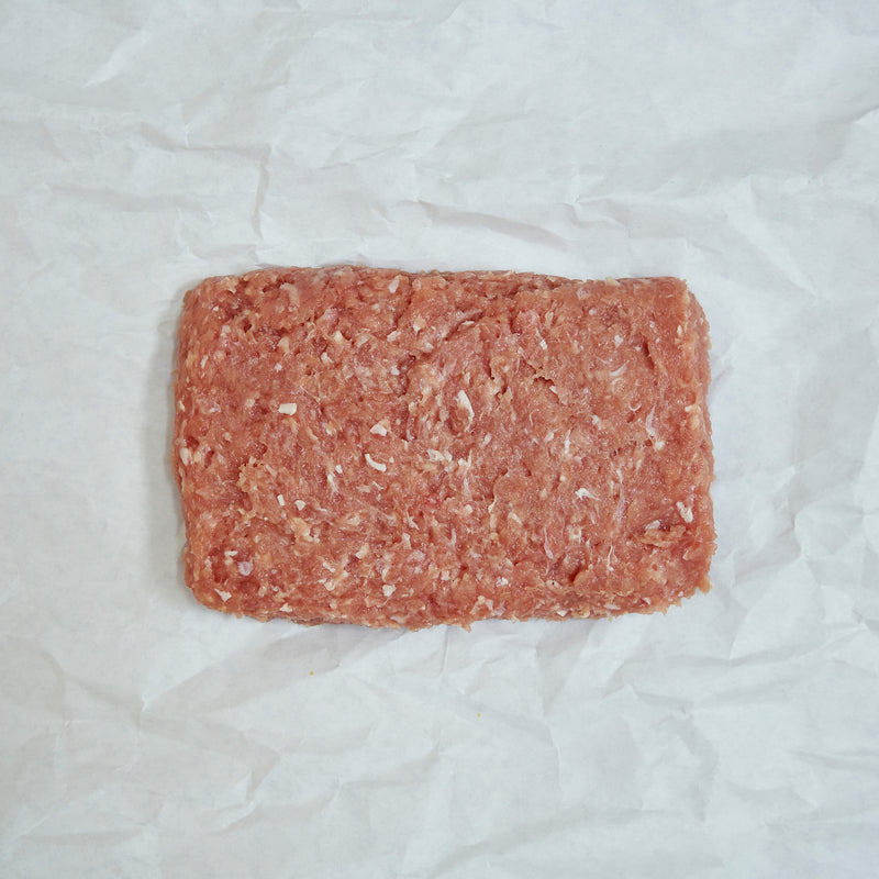 Block of ground chicken on a white paper background