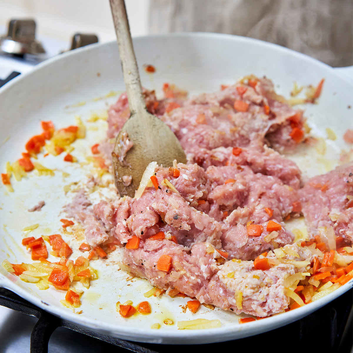 ground chicken and vegetable mixture in a frying pan with a wooden spoon.