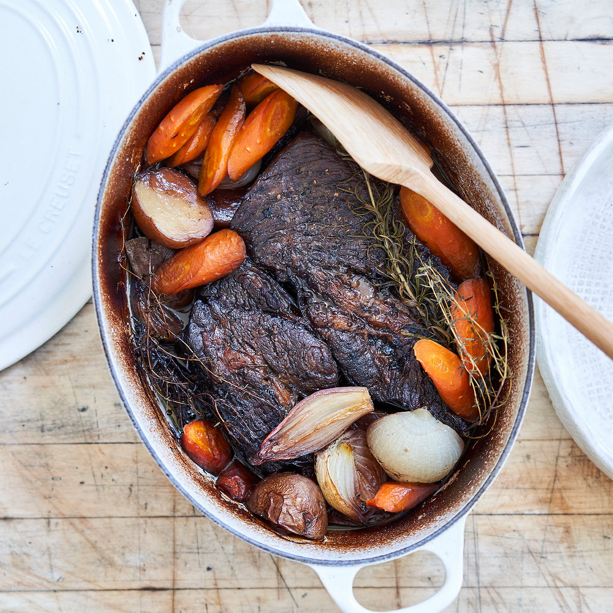 Slow-cooked chuck roast with vegetables in a pot on a wooden surface