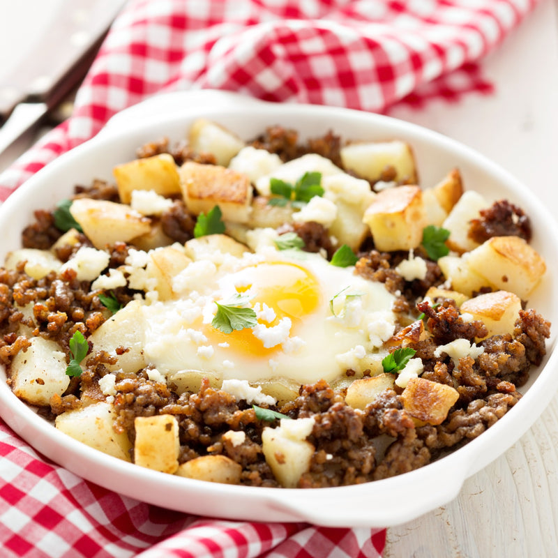 Bowl of ground beef, potatoes, and an egg on a checkered cloth