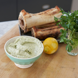 Bowl of Bone Marrow Butter on a wooden surface with bread and herbs in the background