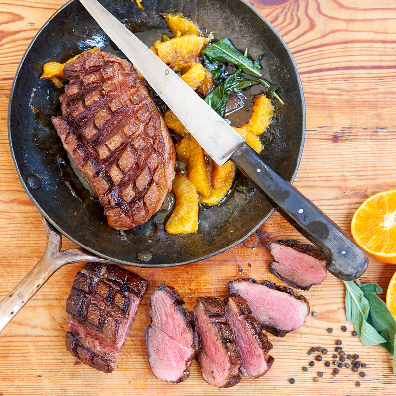 A cooked Moulard duck breast being cut into slices 