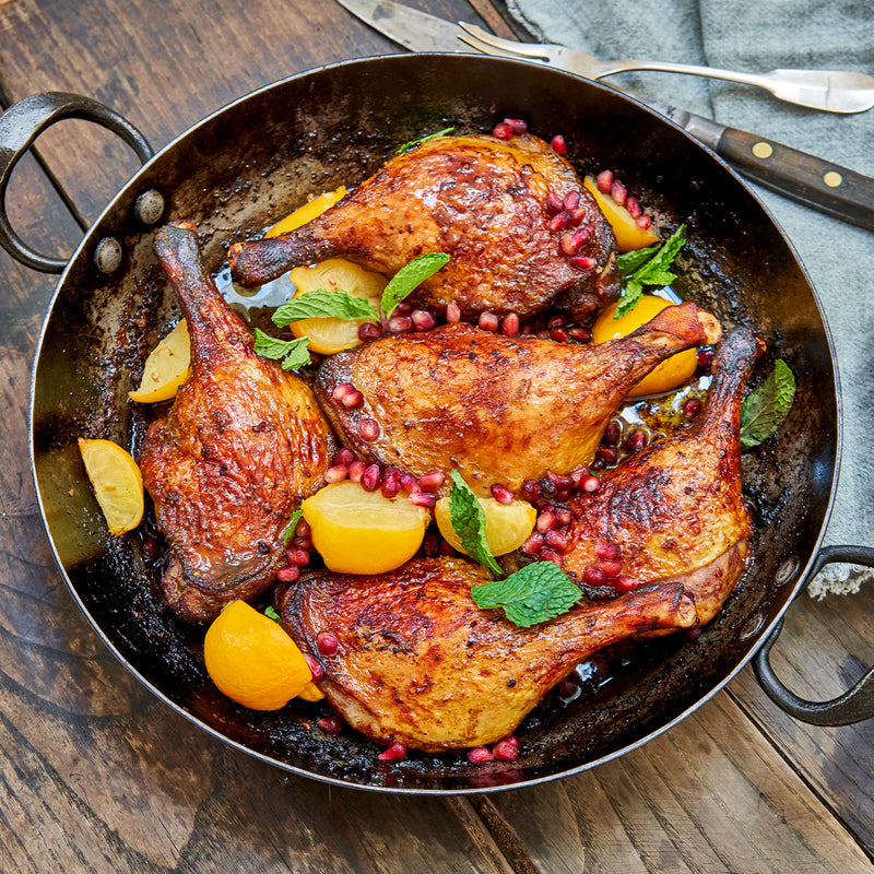 Coked Moulard deck leg quarters with pomegranate seeds, lemon, and basil in a skillet 