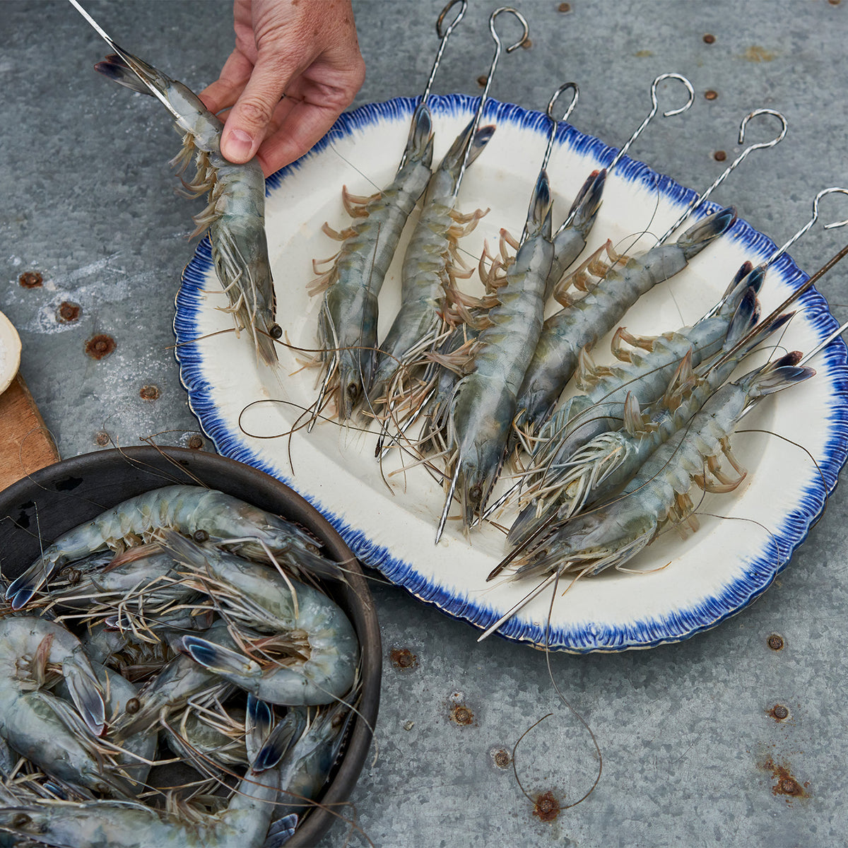 New Caledonia Blue Prawns being prepared on the skewers. They are being placed on skewers longways