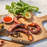 Cooked octopus tentacles on a chopping board