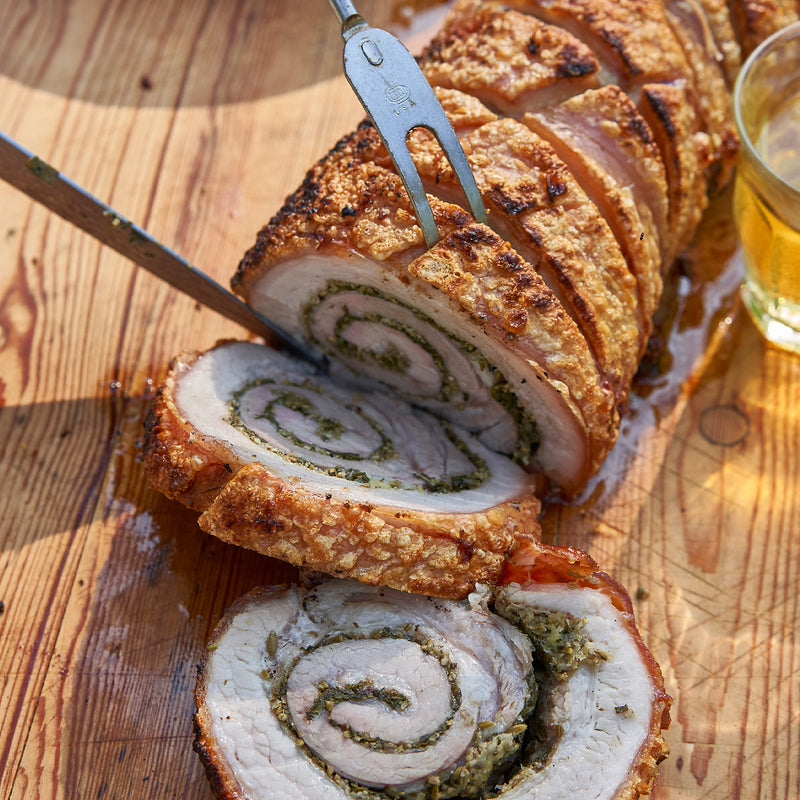 Sliced roasted meat roll with a glass of beer on a wooden surface