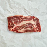 Raw chuck roast on a white crumpled paper background