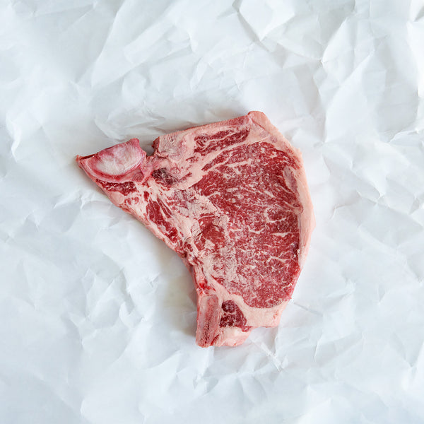 Raw T-bone steak on a white paper background