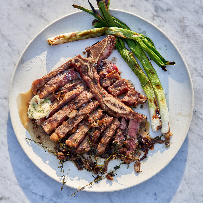 Sliced steak with grilled vegetables on a white plate