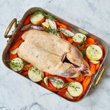 A whole Moulard duck with carrot and onions in a casserole dish 