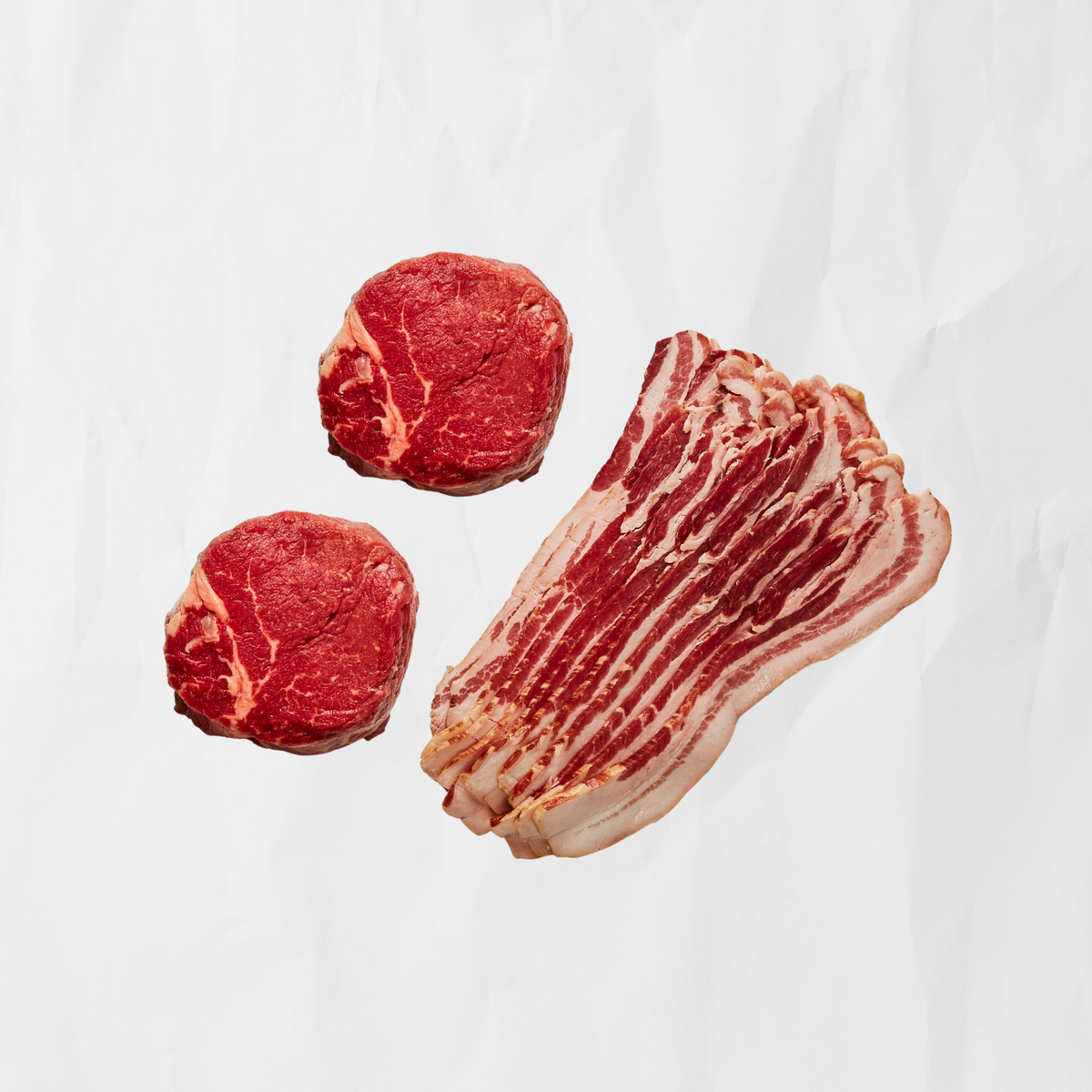 2 raw filet mignons & thick cut bacon on butcher paper