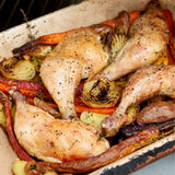 Cooked chicken legs on a sheet pan with onions and carrots. 