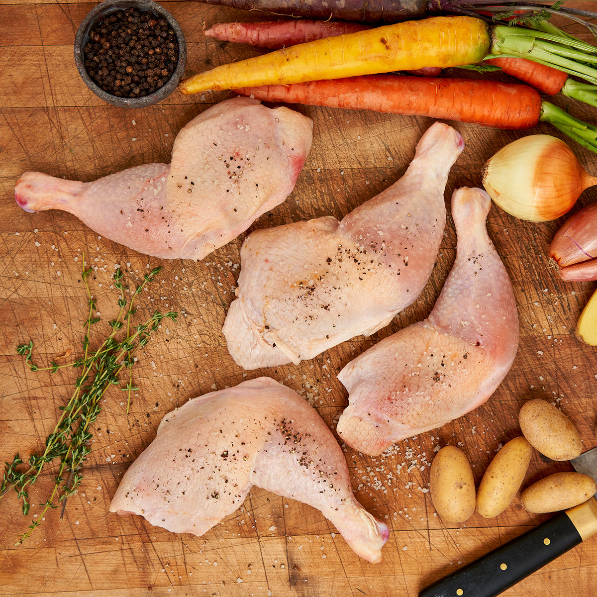 Raw chicken legs on cutting board with salt and pepper on top. 
