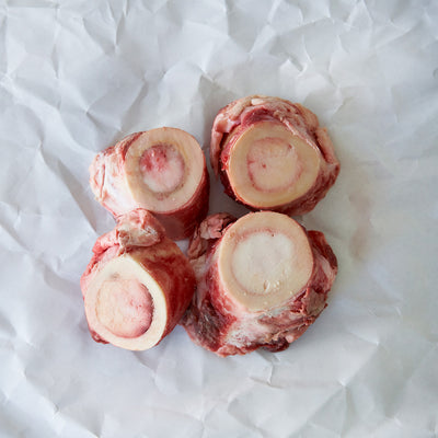 Four raw beef bones on a white paper background