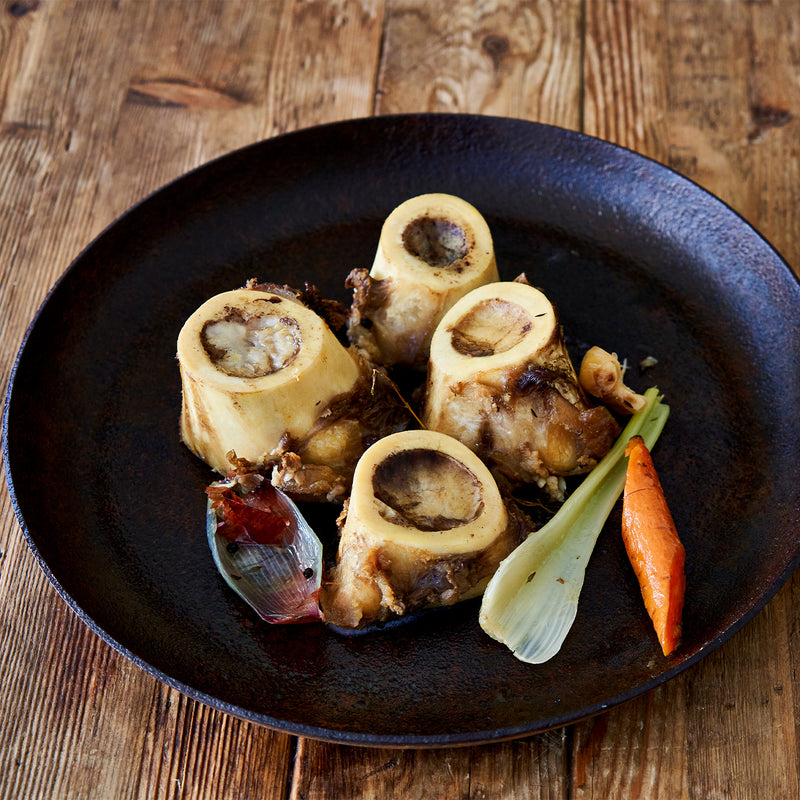 Braised bones with vegetables on a dark plate on a wooden surface