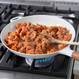 Stir-frying meat in a white pan on a gas stove