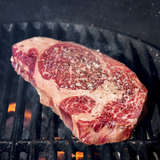 Raw steak on a grill with visible seasoning