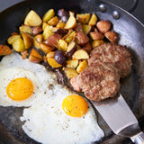 Fried eggs, sausage patties, and roasted potatoes in a skillet.