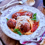 Spaghetti and meatballs on a decorative plate with a wooden table background